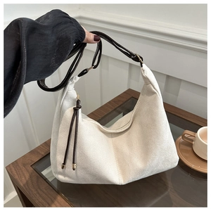 Detail of off-white hobo bag showing soft suede texture and adjustable brown strap