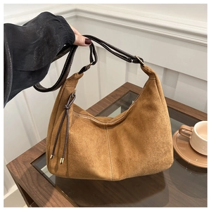 Detail of caramel suede hobo bag featuring decorative white stitching and leather tassels