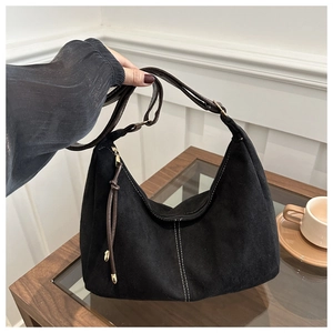 Detail of a black suede hobo bag with contrast stitching and brown adjustable leather strap