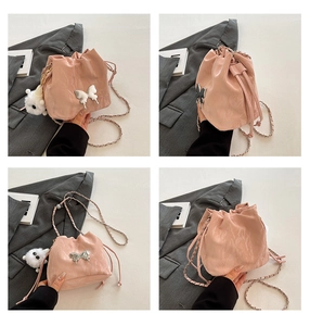 Detail view of pink drawstring bucket bag with silver butterfly and plush charm