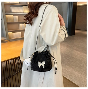 Detail of black velvet drawstring bucket bag with silver butterfly and plush charm