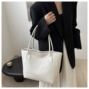 Detailed view of large white woven texture tote bag worn on shoulder for daily use