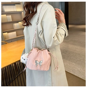 Detail of pink drawstring bucket bag with silver butterfly charm and plush pompom pendant