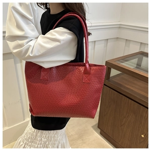 Detail of red woven texture tote bag with long handles shown on a model for daily use