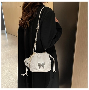 White drawstring bucket bag with silver butterfly and plush charm shown on model