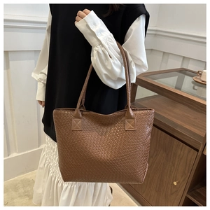 Close-up of brown woven texture and slim leather straps on a large tote bag