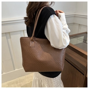 Detailed side view of a brown woven texture tote bag worn by a model for daily style