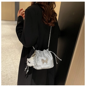 Detail of silver drawstring bucket bag featuring metallic texture and butterfly charm