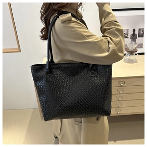 Close-up of the black woven leather texture and shoulder strap of this large tote bag