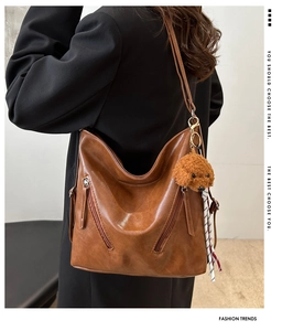 Dettaglio della borsa tote in pelle PU marrone con doppie cerniere e ciondolo a forma di cane