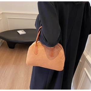 Close-up of caramel brown suede texture and leather handle on the Boston handbag