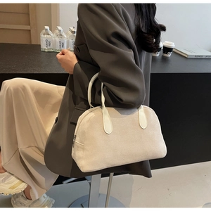 Minimalist beige suede Boston bag with large capacity held by a woman in elegant suit