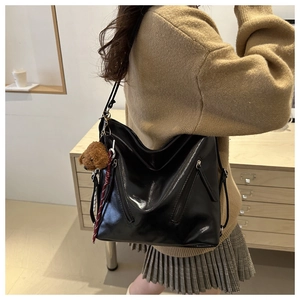 Borsa tote nera lucida con cerniera diagonale e ciondolo a forma di orsetto di peluche
