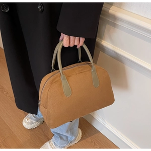 Detailed view of brown suede Boston bag with green handles and vintage bowling design