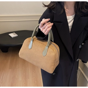 Detail of Boston bag with brown suede fabric, olive green handles and metal zipper