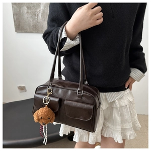 Détail d'un sac à bandoulière en cuir PU marron foncé avec poches avant et charme en peluche