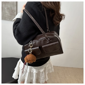 Detalle de un bolso de hombro retro marrón con dos bolsillos y colgante de perro