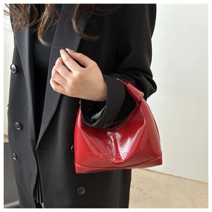 Detail of red patent leather crescent bag with embossed letters and gold zipper