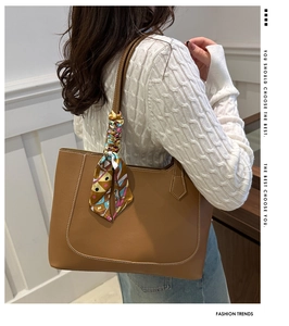 Brown leather tote bag featuring white contrast stitching and silk scarf wrapped handle