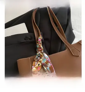 Detail of brown leather tote bag featuring a colorful silk scarf wrap and white stitching