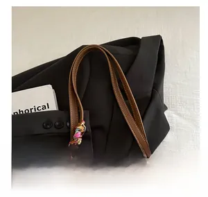 Detail of brown leather tote bag with white stitching and colorful silk scarf on handle