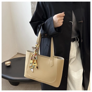 Detail of khaki tote bag with colorful geometric silk scarf tied on the handle