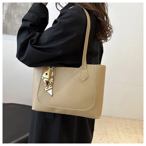 Close-up of khaki leather tote bag with a silk scarf tied on the handle for women