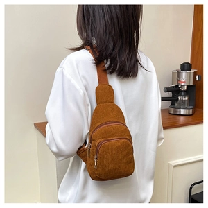 Detail of a brown corduroy chest bag with adjustable strap worn by a casual model