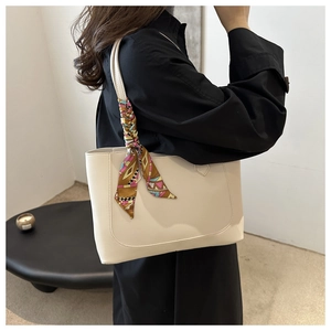 Beige tote bag with colorful silk scarf detail worn by a model in a minimalist setting