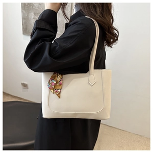 Chic cream tote bag with silk scarf detail shown on a model in a black trench coat