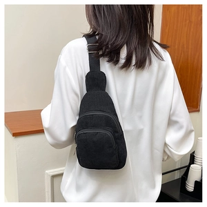 Detail of black corduroy chest bag featuring two zipper compartments and adjustable strap