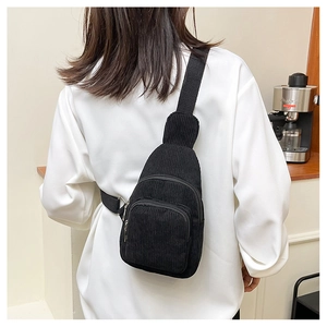 Detail view of black corduroy chest bag texture with adjustable strap and dual front pockets