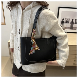 Detail of a black leather tote with white contrast stitching and a silk scarf on handle