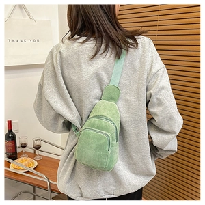 Light green corduroy chest bag shown worn by a model in a cozy indoor setting