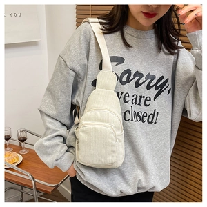 Close-up of beige corduroy crossbody bag worn by model in a warm lifestyle setting