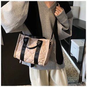 Sac bandoulière en nylon matelassé beige avec lanières noires porté par un mannequin
