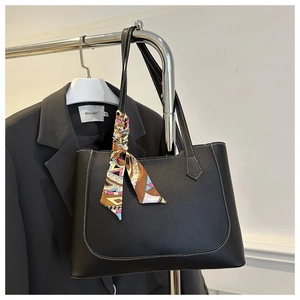 Detail of black tote bag with white contrast stitching and colorful silk scarf handle wrap