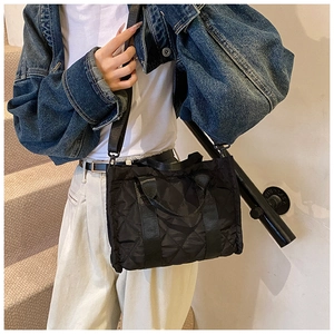 Detail of black quilted nylon handbag showing the classic diamond stitch and crossbody strap