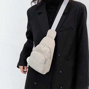 Detail of cream corduroy chest bag featuring vertical stripes and adjustable strap on a model