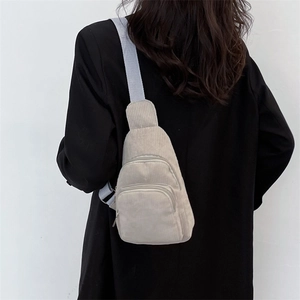 Rear view of model wearing a light gray corduroy chest bag with double front zippers