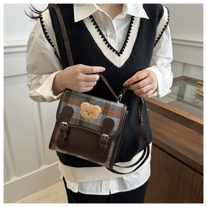Detail of British style plaid crossbody bag with teddy bear patch and buckle straps
