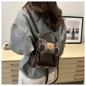 Rear view of woman wearing a retro plaid backpack with a plush bear patch and leather detail