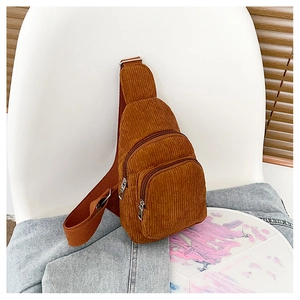 Close-up of brown corduroy crossbody bag texture with adjustable strap and metal zippers