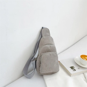 Detail of grey corduroy crossbody chest bag with adjustable strap and dual zippers