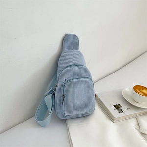 Detail of light blue corduroy crossbody bag with multiple zipper pockets and wide strap
