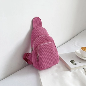 Detail of rose red corduroy sling bag featuring three zipper pockets and thick woven strap