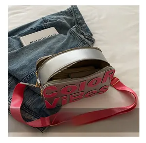 Dettaglio della borsa fotografica grigio argento con lettere in pelle rosa e doppia zip