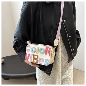 Dettaglio della borsa beige con lettere 3D colorate e tracolla viola chiaro