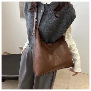 Detail view of large dark brown leather tote bag showing textured surface and stitching