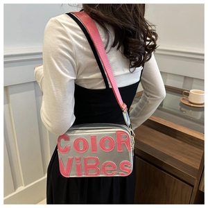 Dettaglio borsa fotografica argento con scritta Color ViBes rosa e tracolla larga